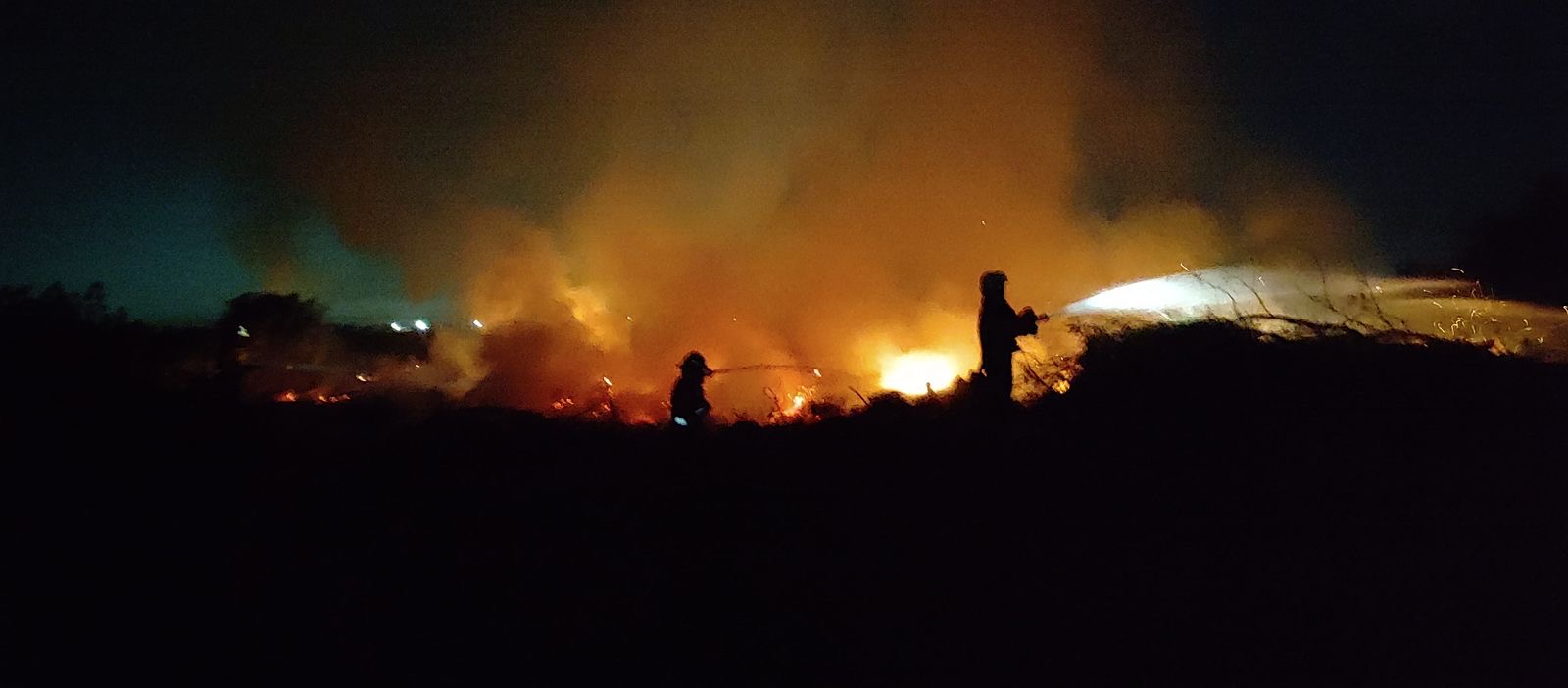 Bomberos Voluntarios de Funes combatiendo un incendio de pastizales de noche cerca del barrio Islas Malvinas