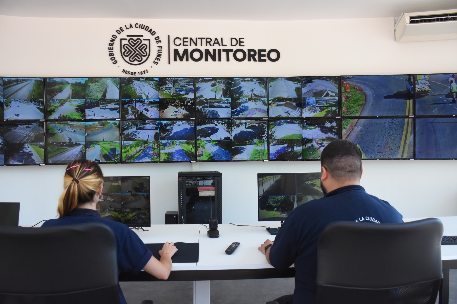 Operadores de la Central de Monitoreo Funes observan la pared de pantallas con feeds de las cámaras de la ciudad
