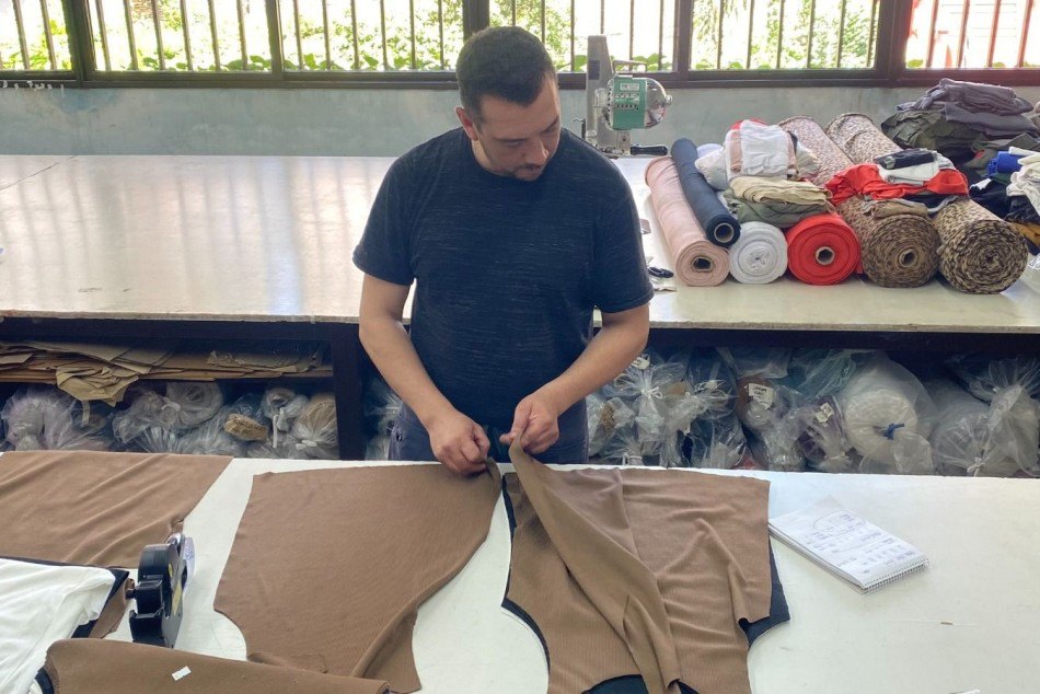Operario corta tela en un taller textil, empleo en Rosario