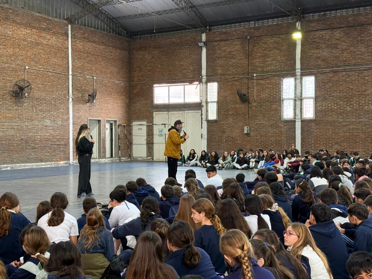 Hernán Danolfo hablando ante los alumnos sentados en el gimnasio del Paul Harris
