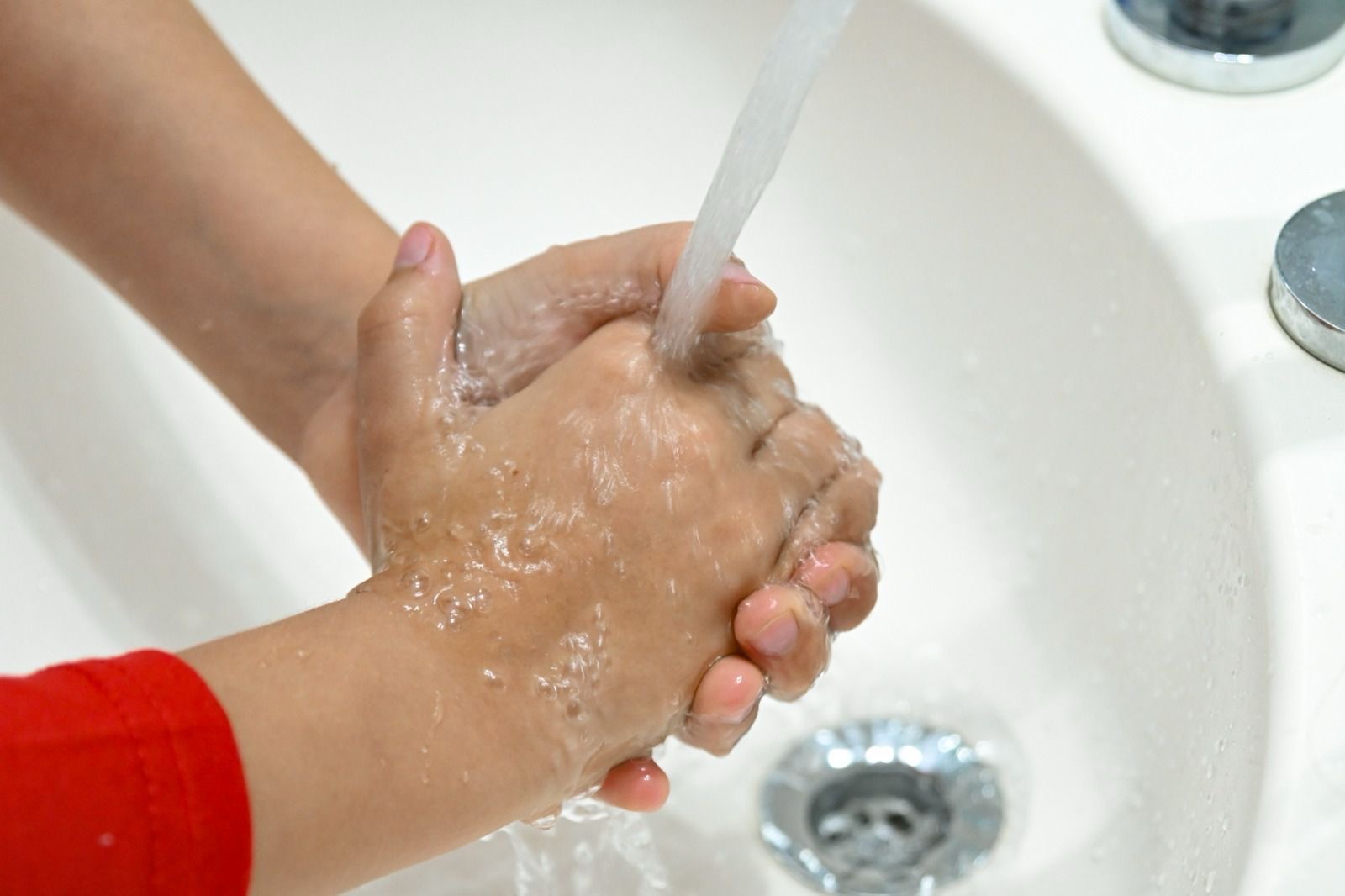 Un niño se lava las manos con agua y jabón, medida clave para la prevención de enfermedades respiratorias