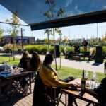Locro y folklore en Estancia Damfield para celebrar el 25 de Mayo Locro y folklore en Damfield: terraza al aire libre con mesas y músicos