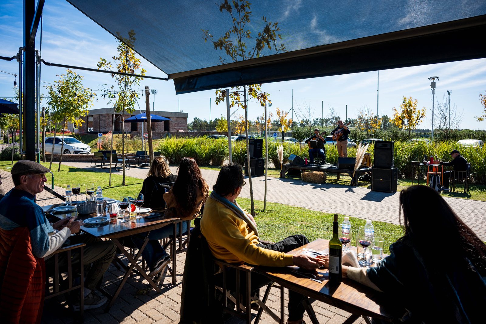 Locro y folklore en Damfield: terraza al aire libre con mesas y músicos