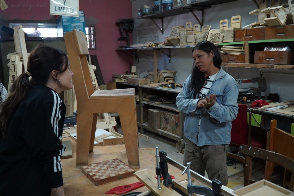 Mariana, carpintera de El Obrador Rosario, conversa con una joven en su taller