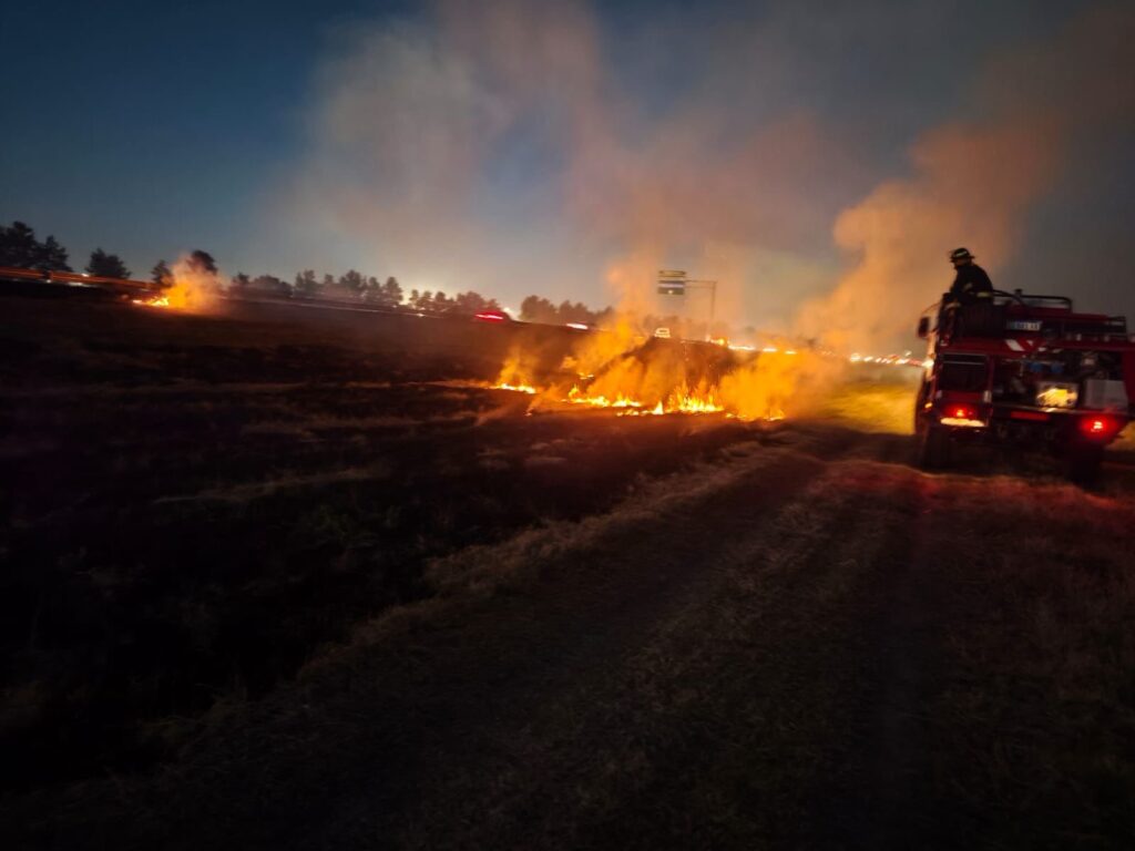Bomberos de Funes combaten un incendio de pastizal en autopista Rosario-Córdoba al atardecer