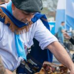 Asador con poncho y boina corta el Asado a la Estaca en Funes