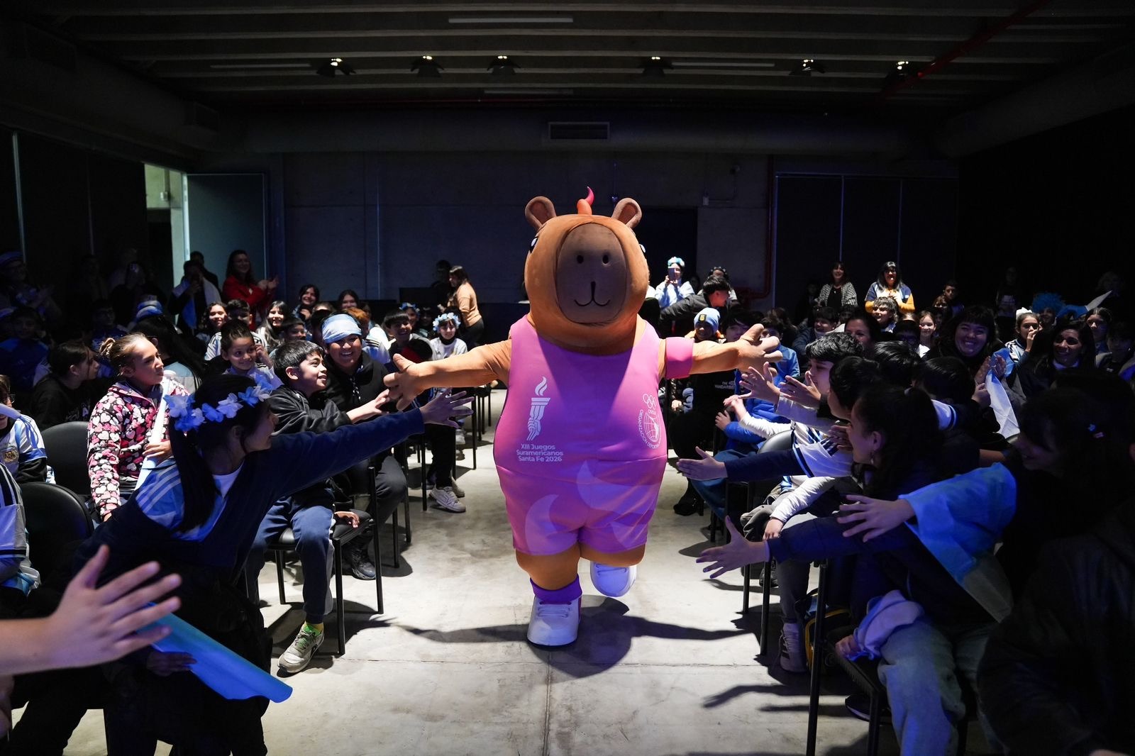 La mascota Capi de los XIII Juegos Suramericanos saluda a los alumnos durante la jornada