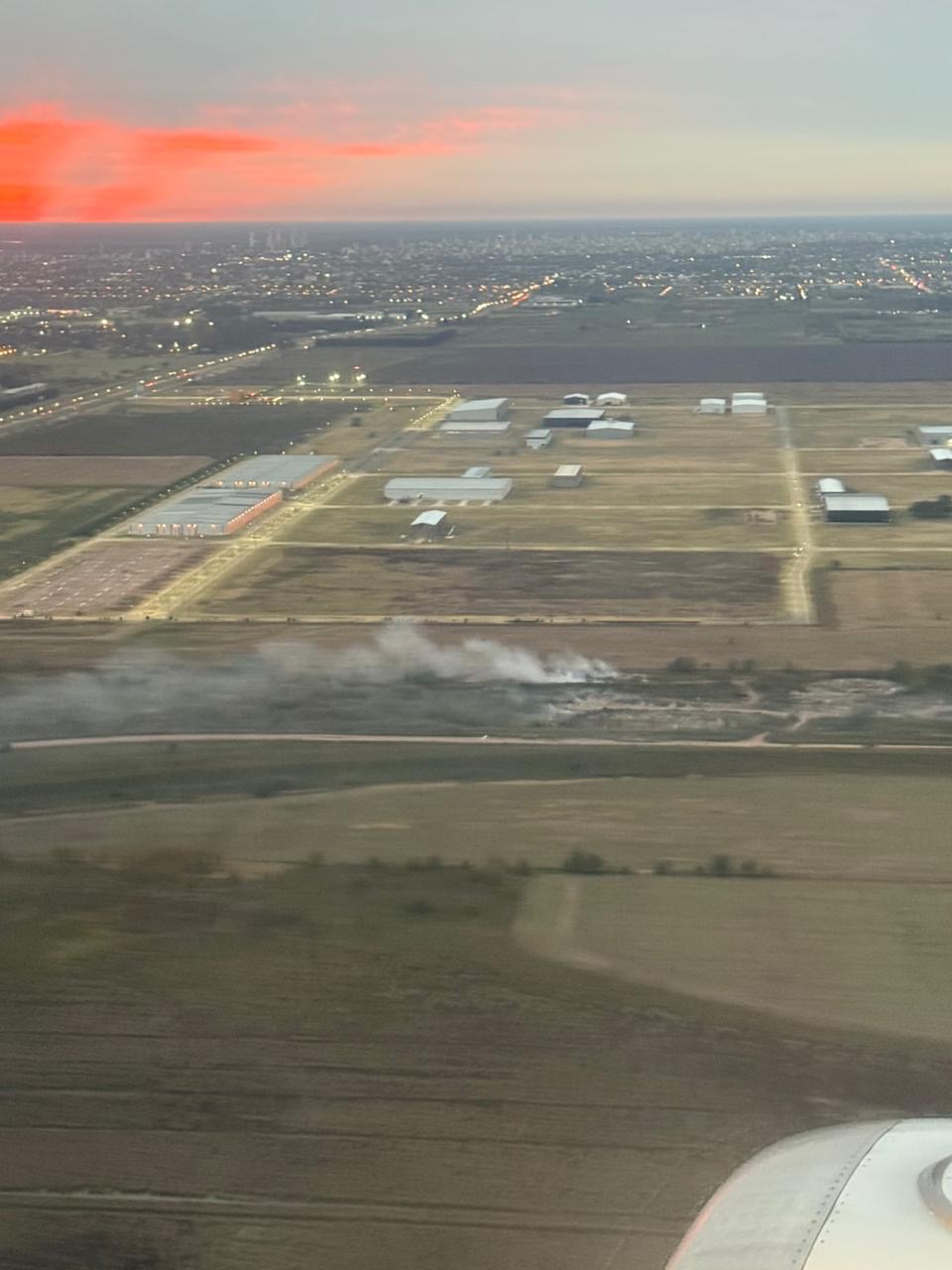 Vista aérea de la cava de Funes con humo de quemas y el Parque Industrial Metropolitano al fondo