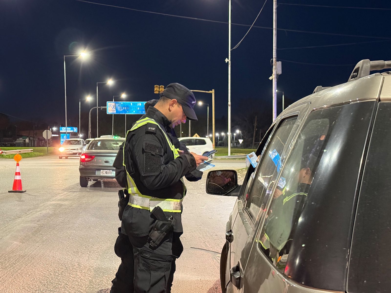 Control vehicular en Roldán: un efectivo policial verifica la documentación de un conductor durante el operativo