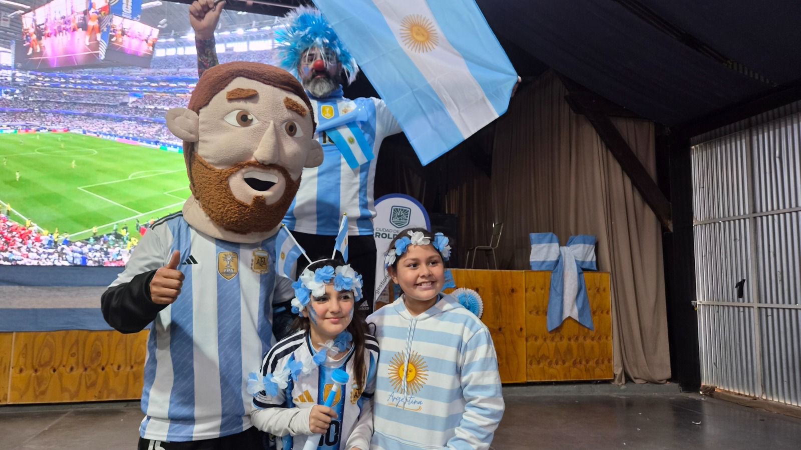 Niñas con la mascota de la Selección y banderas argentinas durante el Fan Fest de Roldán