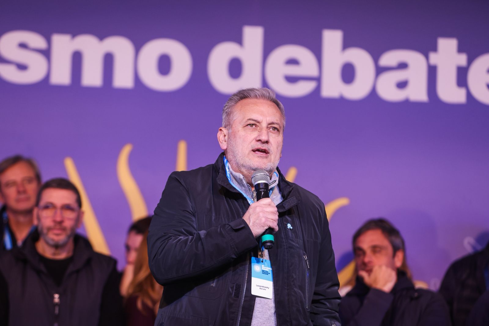 Marcelo Lewandowski habla con micrófono ante el banner de El Peronismo Debate en Concepción del Uruguay