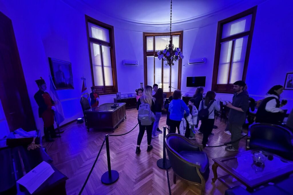 Visitantes recorren una sala del Museo Histórico de Santa Fe iluminada de azul