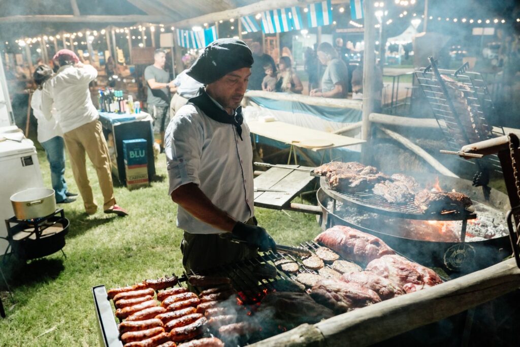 Asador prepara asado a la estaca y chorizos en la Peña Folclórica en Funes del Paseo del Artesano