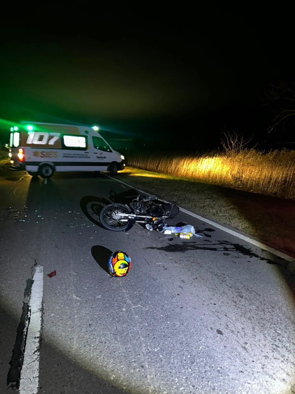 Una ambulancia del Sies junto a la motocicleta caída y el casco sobre la Ruta 33, durante la noche