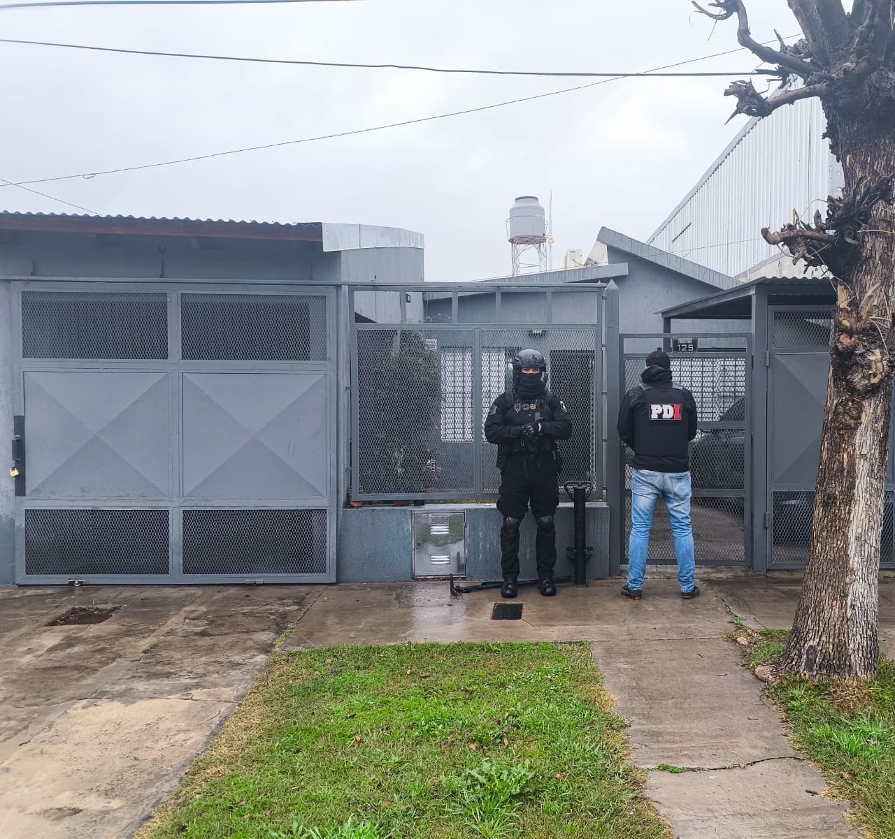 Dos efectivos de la PDI frente a la vivienda allanada en Capitán Bermúdez durante el operativo