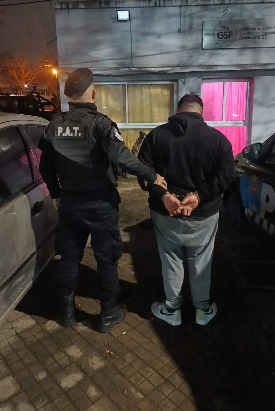 Un efectivo traslada de espaldas al hombre aprehendido frente a la Comisaría 25ª, durante la noche