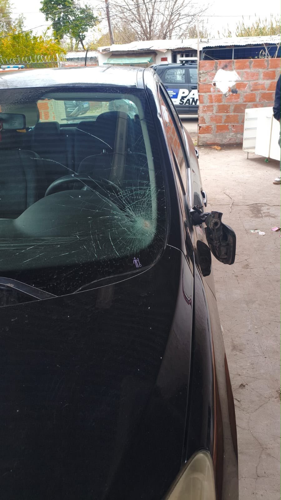 Parabrisas y espejo rotos de un automóvil dañado, secuestrado en un procedimiento policial en Rosario