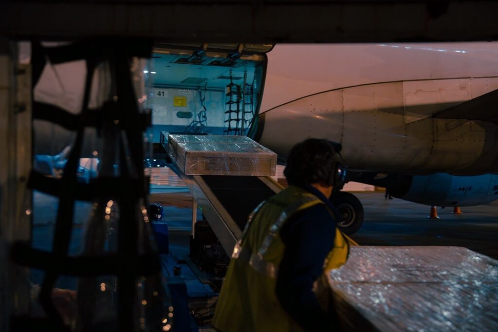 Un operario supervisa la carga de mercadería en la bodega de un avión durante una operación de carga aérea