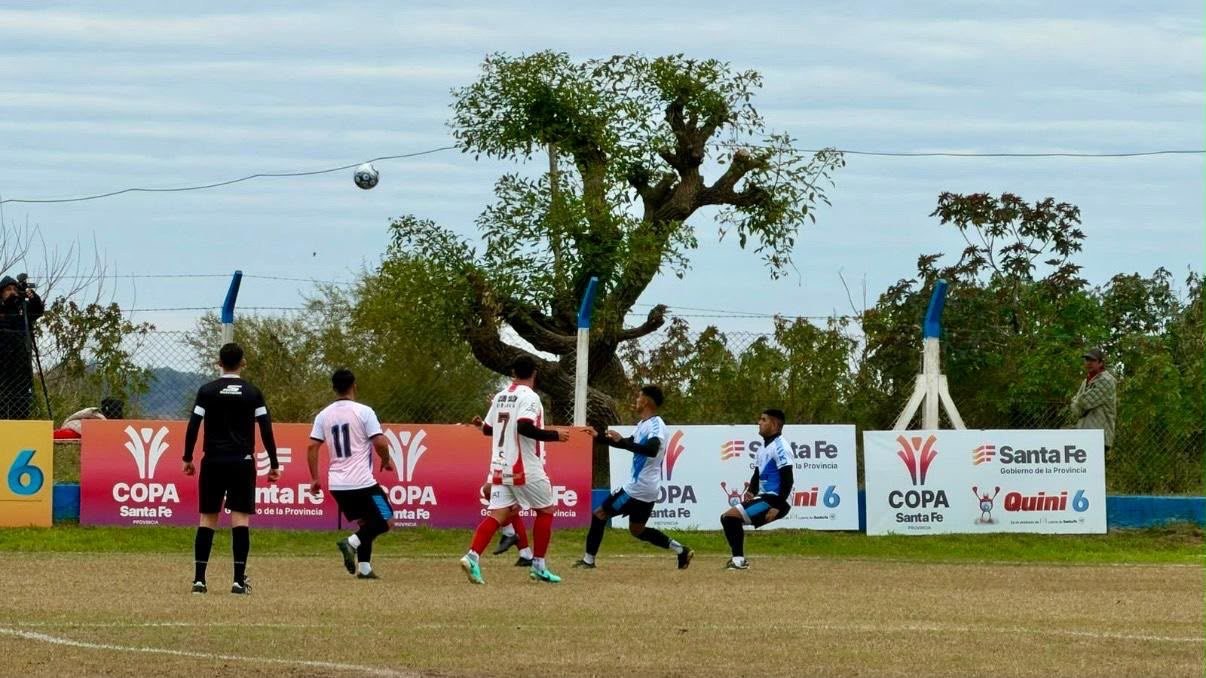 Jugadores disputan un partido de fútbol de la Copa Santa Fe, con la cartelería del certamen