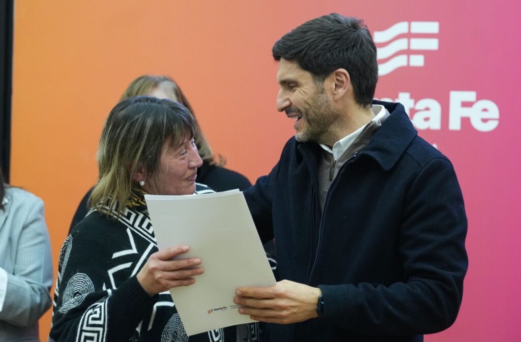 El gobernador entrega la escritura de su vivienda a una vecina, en el acto de regularización dominial en Rosario