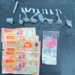 Envoltorios con sustancias y billetes secuestrados por la Policía sobre el capot de un móvil