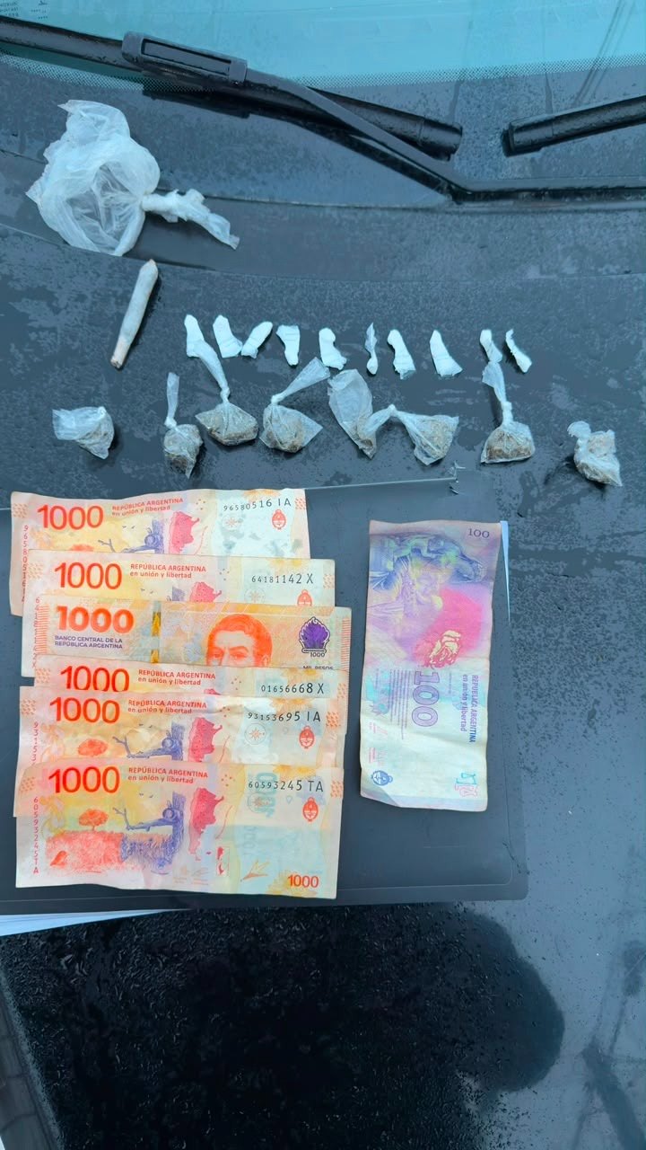 Envoltorios con sustancias y billetes secuestrados por la Policía sobre el capot de un móvil