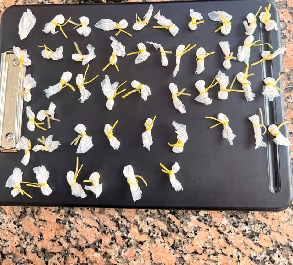 Decenas de envoltorios blancos atados con hilo amarillo, ordenados sobre una tabla, tras el secuestro policial