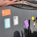 Una escopeta de doble caño secuestrada por la Policía, apoyada sobre el capot de un móvil junto a otros elementos