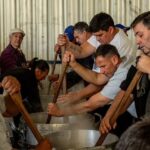 Soldini se prepara para la 4.ª Fiesta del Arroz: cuándo es, dónde y cuánto sale la porción Un grupo de cocineros revuelve con palas de madera las ollas de arroz durante la Fiesta del Arroz de Soldini