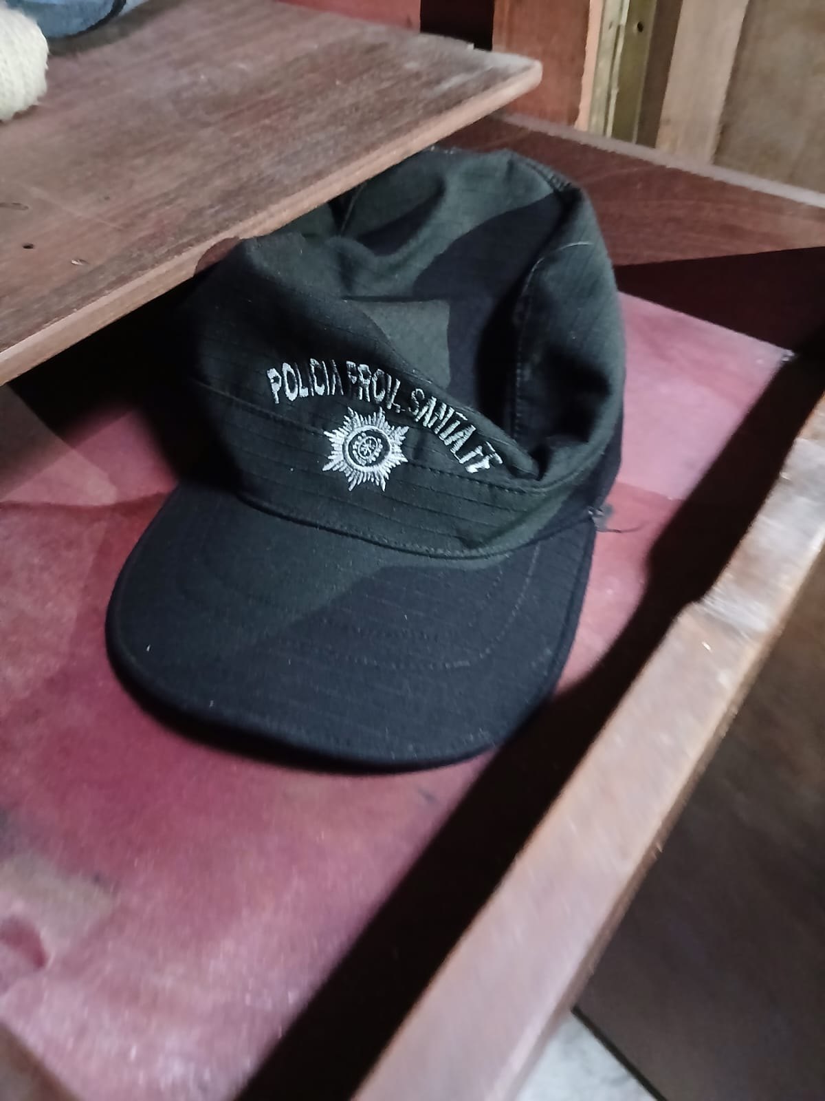 Una gorra negra con el escudo bordado de la Policía de la Provincia de Santa Fe sobre una silla