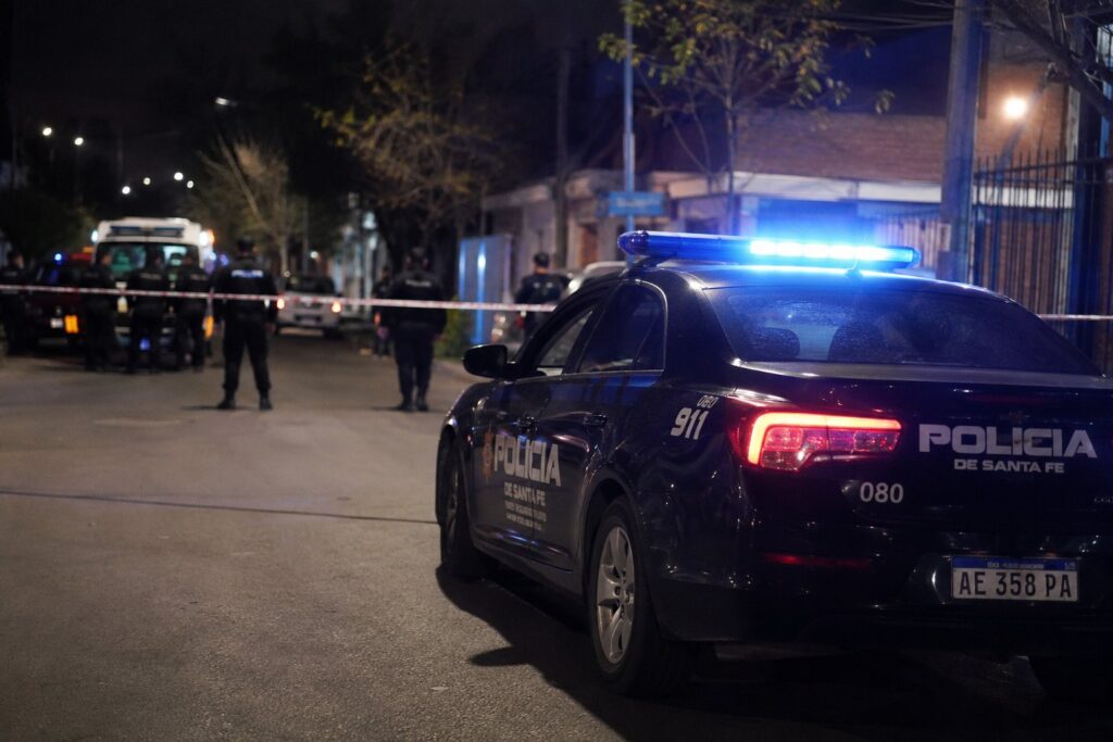 Un patrullero de la Policía de Santa Fe y personal en la escena de un homicidio, de noche, en Rosario