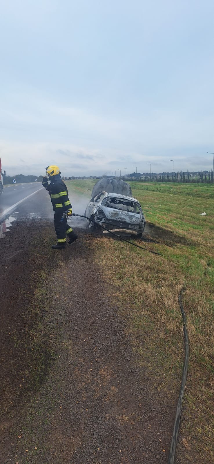 Un bombero de Funes extingue el incendio de un automóvil sobre la Autopista a Córdoba