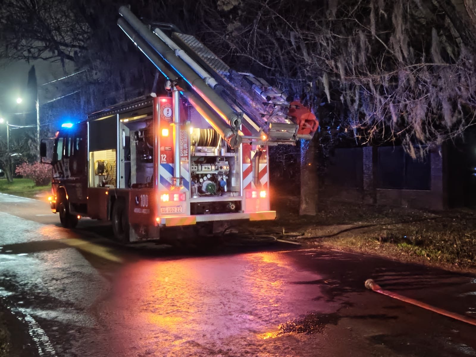 Una línea de manguera tendida sobre la calle mojada junto a la unidad de Bomberos Voluntarios de Funes
