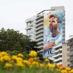 Mural de Messi en Rosario pintado en un edificio, con flores en primer plano