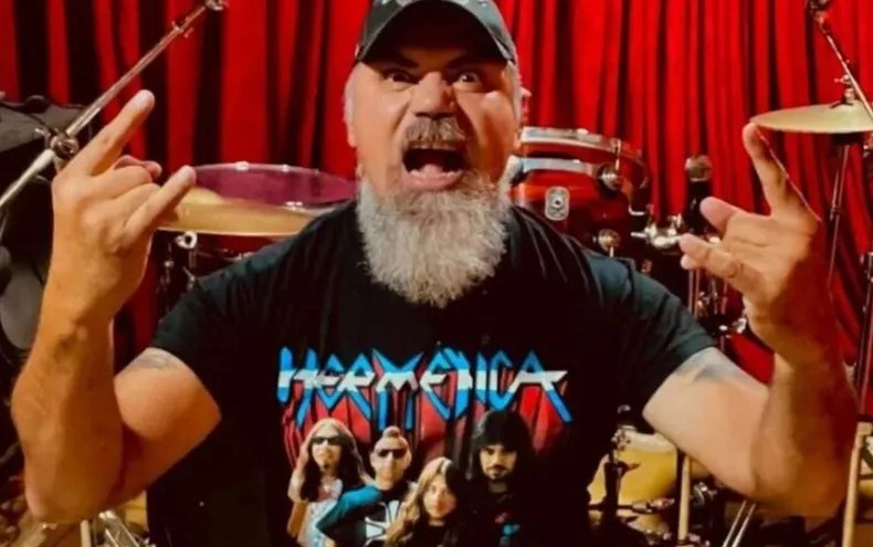 Pato Strunz con los brazos en alto y palillos en la mano, frente a su batería, con una remera de Hermética