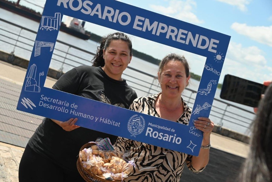 Dos emprendedoras posan con el marco de Rosario Emprende, junto al río en Rosario