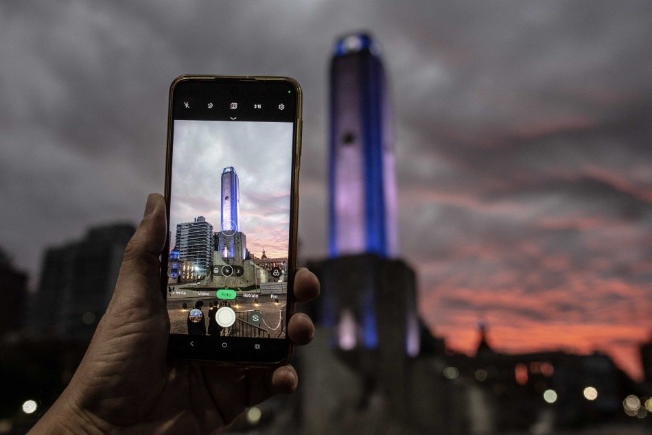 Un visitante fotografía el Monumento Nacional a la Bandera, ícono del turismo en Rosario, iluminado al atardecer