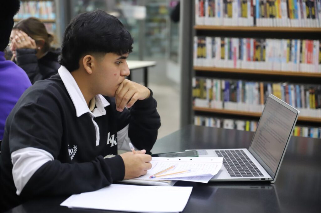 Un estudiante estudia con su notebook en la biblioteca de la UNR