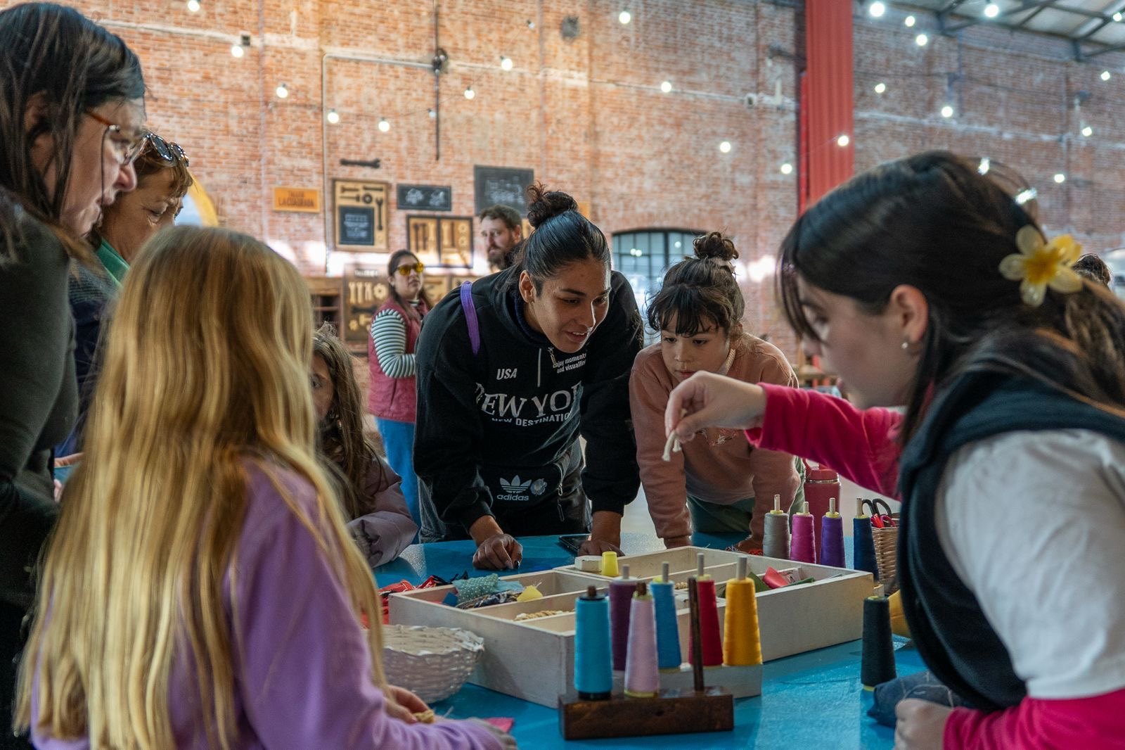 Chicos y adultos participan de un taller textil con hilos de colores en las Vacaciones Copadas