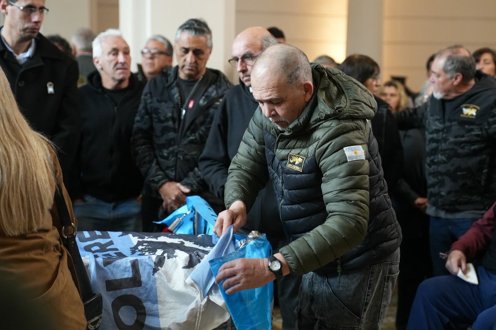 Un veterano de guerra acomoda una bandera de Malvinas durante la despedida a Rubén Rada